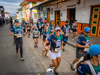 Runner celebrating her participation in the Salento Trail Challenge with her event medal, surrounded by Salento’s traditional architecture.